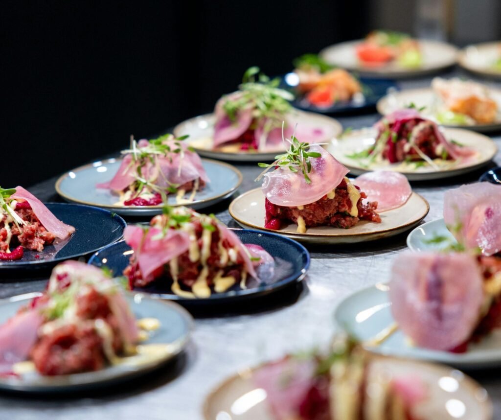 Assorted plated appetizers topped with pickled radish and microgreens on a restaurant tasting menu table.